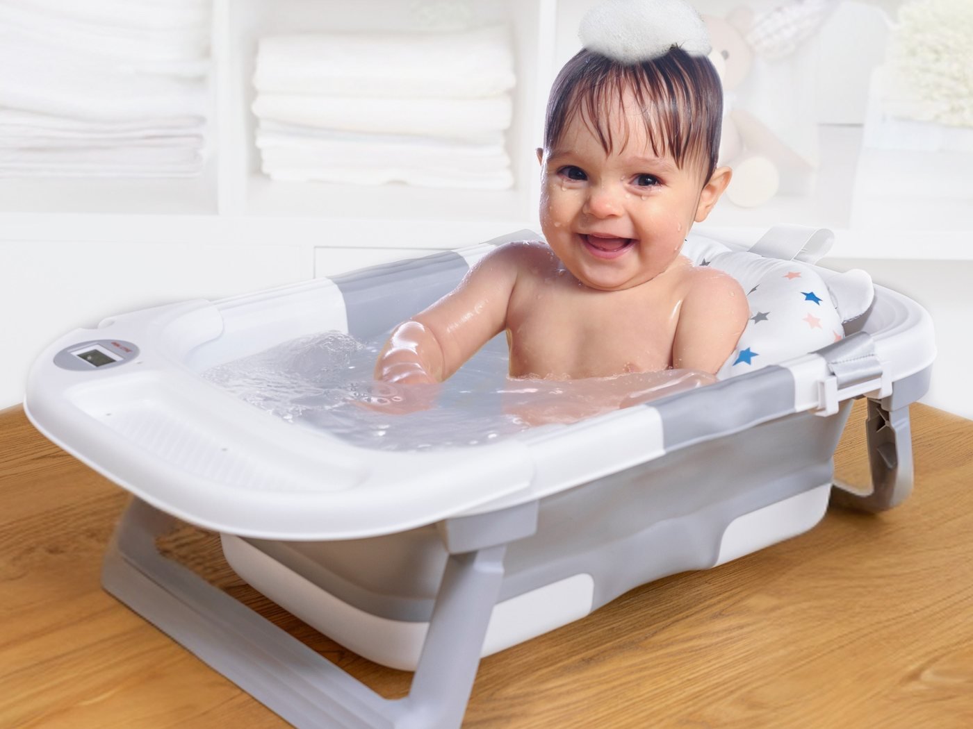 Bébé souriant dans la baignoire pliable avec thermomètre